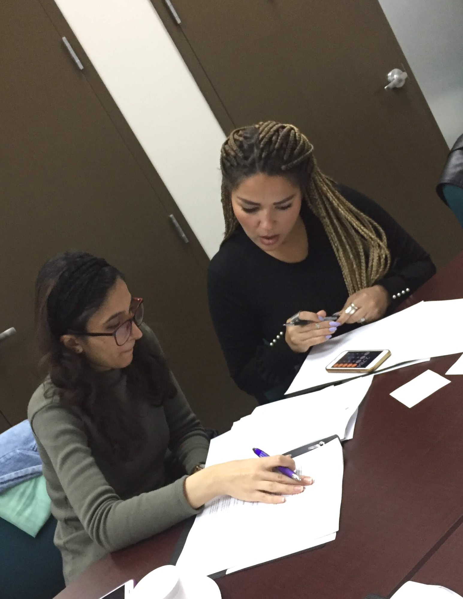 Two women sit at a table looking over worksheets at the financial literacy and empowerment workshop.