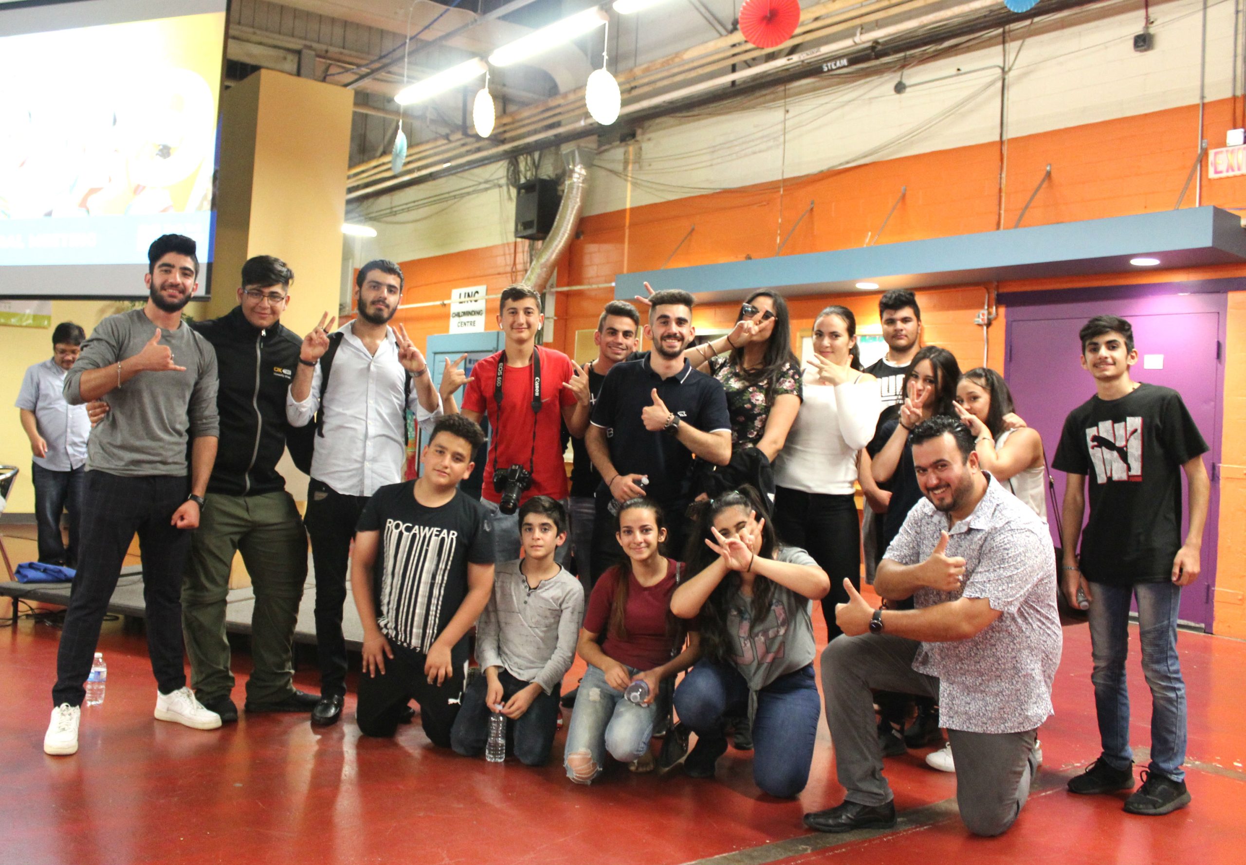 Group of young people smiling and holding up peace signs.