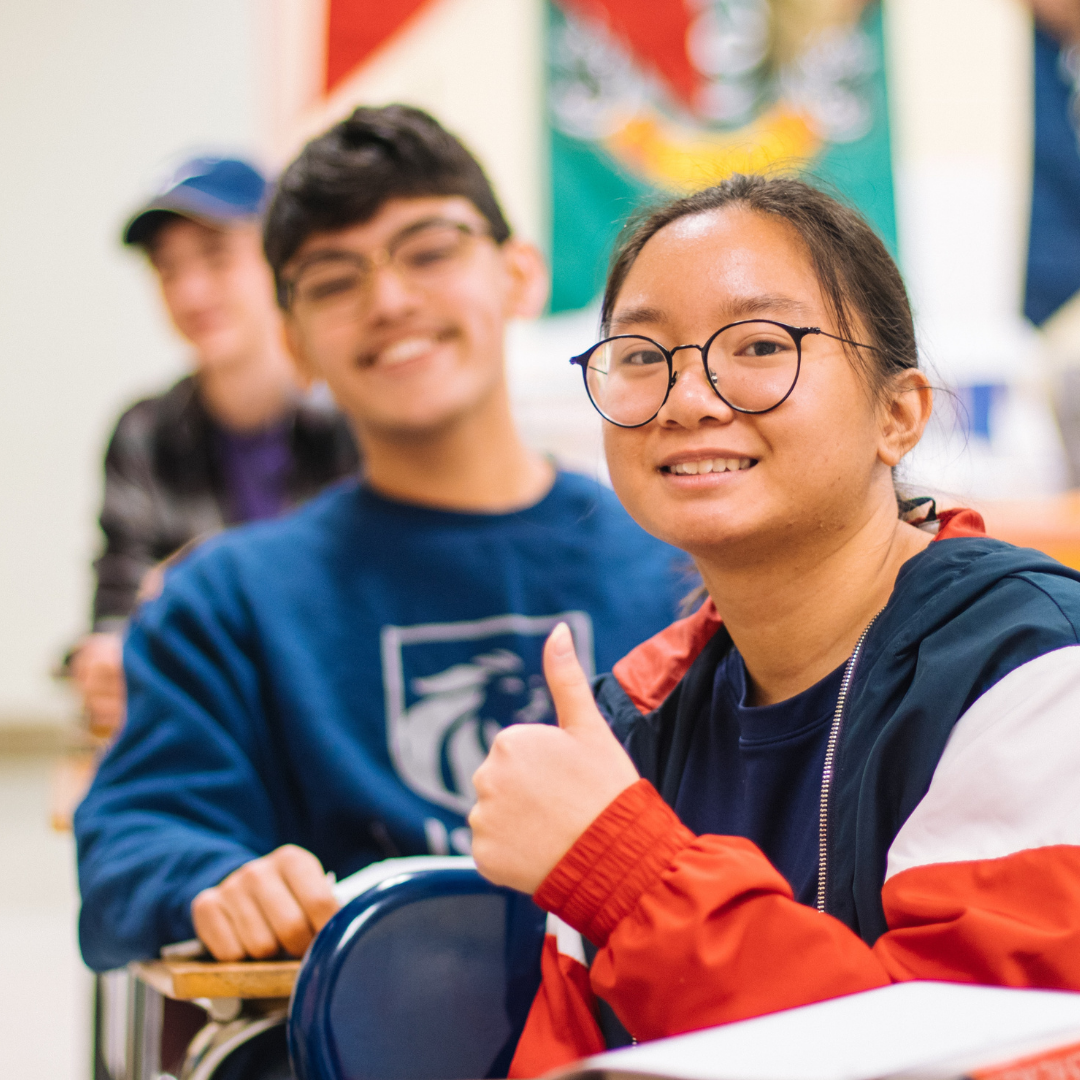 Two youth in a classroom smiling at the camera.