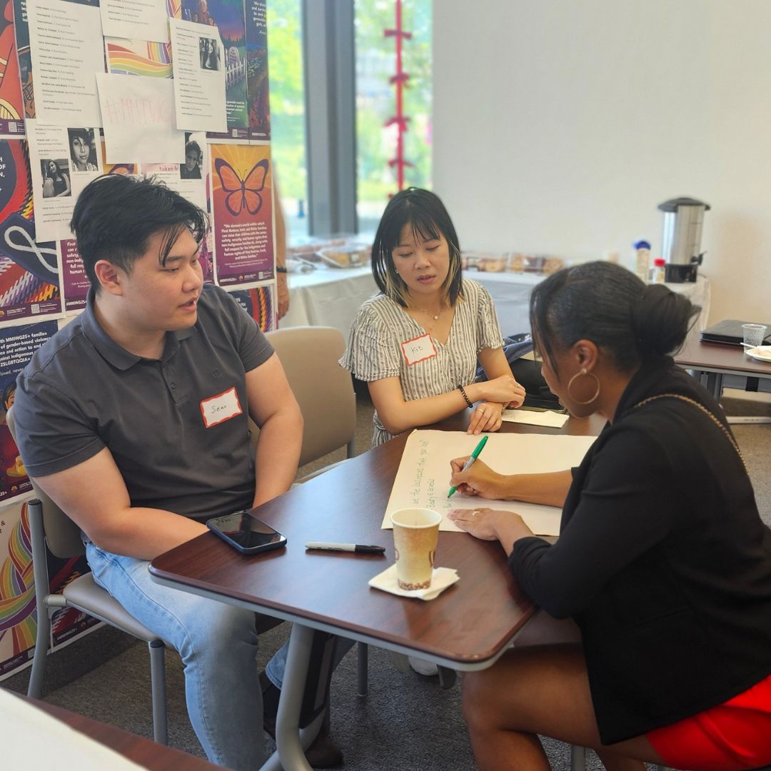 a group of people sitting at a table brainstorming and jotting down ideas on chart paper