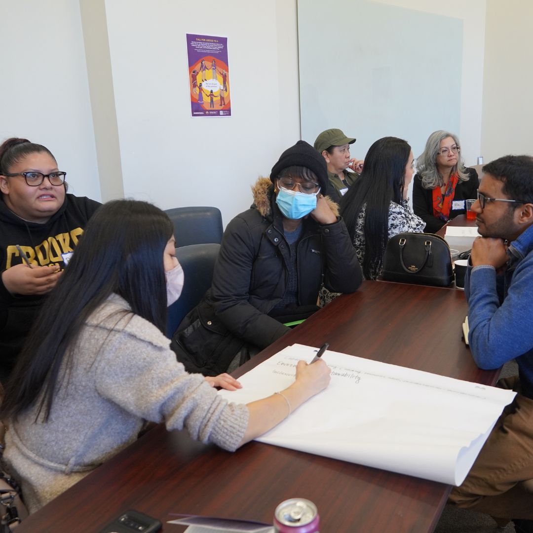 a group of people sitting at tables discussing ideas and jotting it down on chart paper