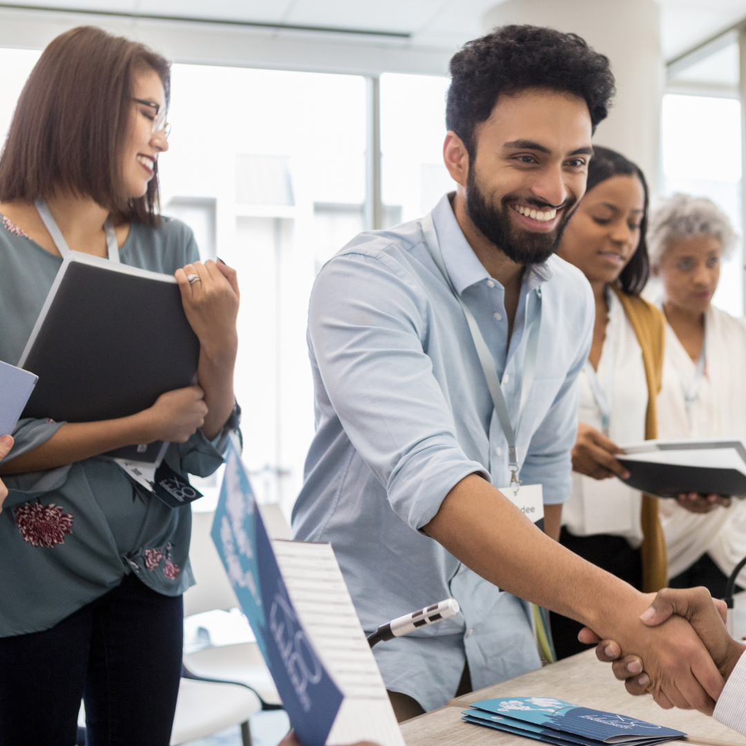 A gathering of people exchanging handshakes in a meeting, illustrating unity and professional relationships.