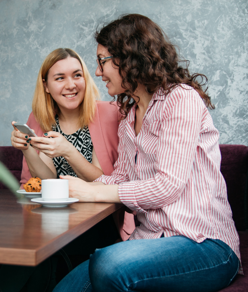 Two women sitting together at a table, enjoying each other's company in a relaxed and friendly atmosphere.