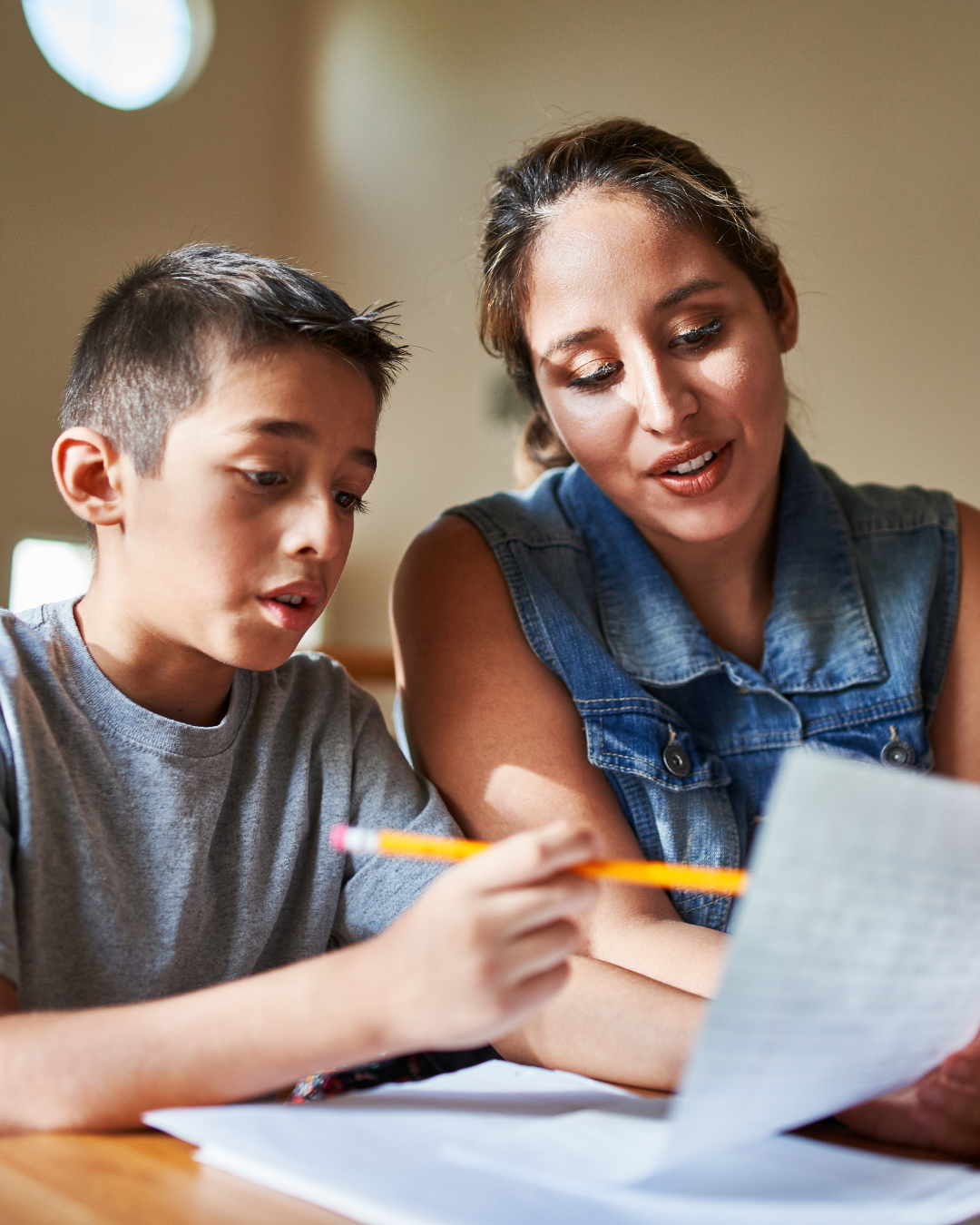 A woman and a boy engage in a collaborative effort on a paper, demonstrating teamwork and concentration in their work.