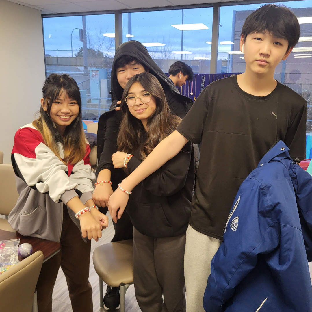A group of youth holding out their hands to show the bracelets they made