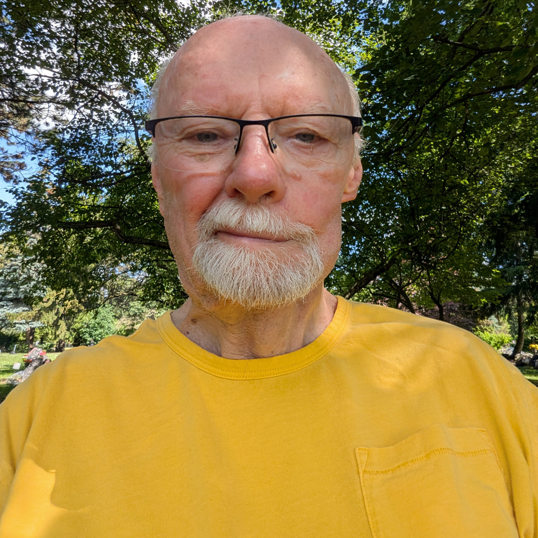 A picture of Michael standing outside in front of trees.
