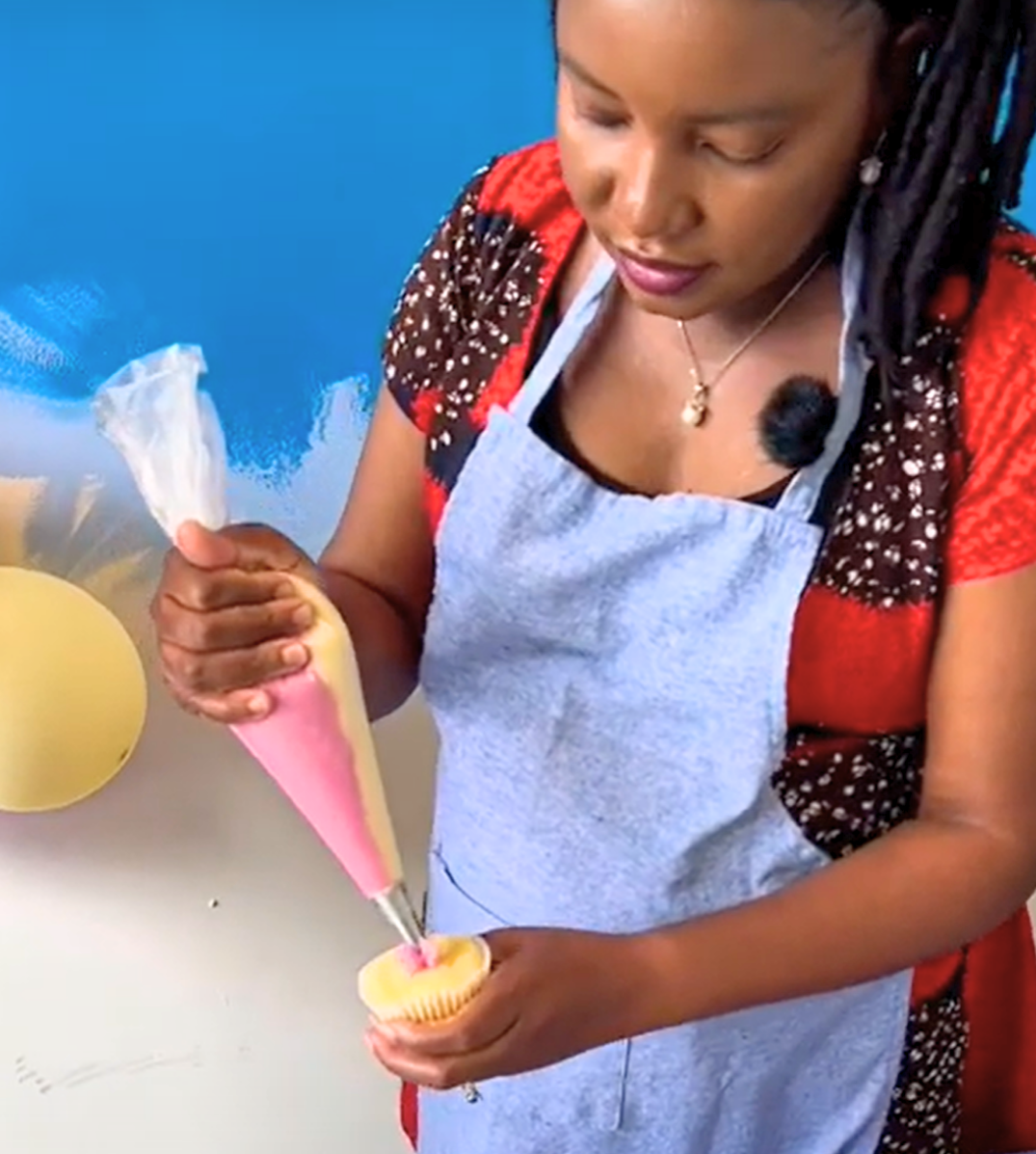A woman decorates a cupcake.