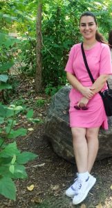 Zahra smiling, posing in a forested area.