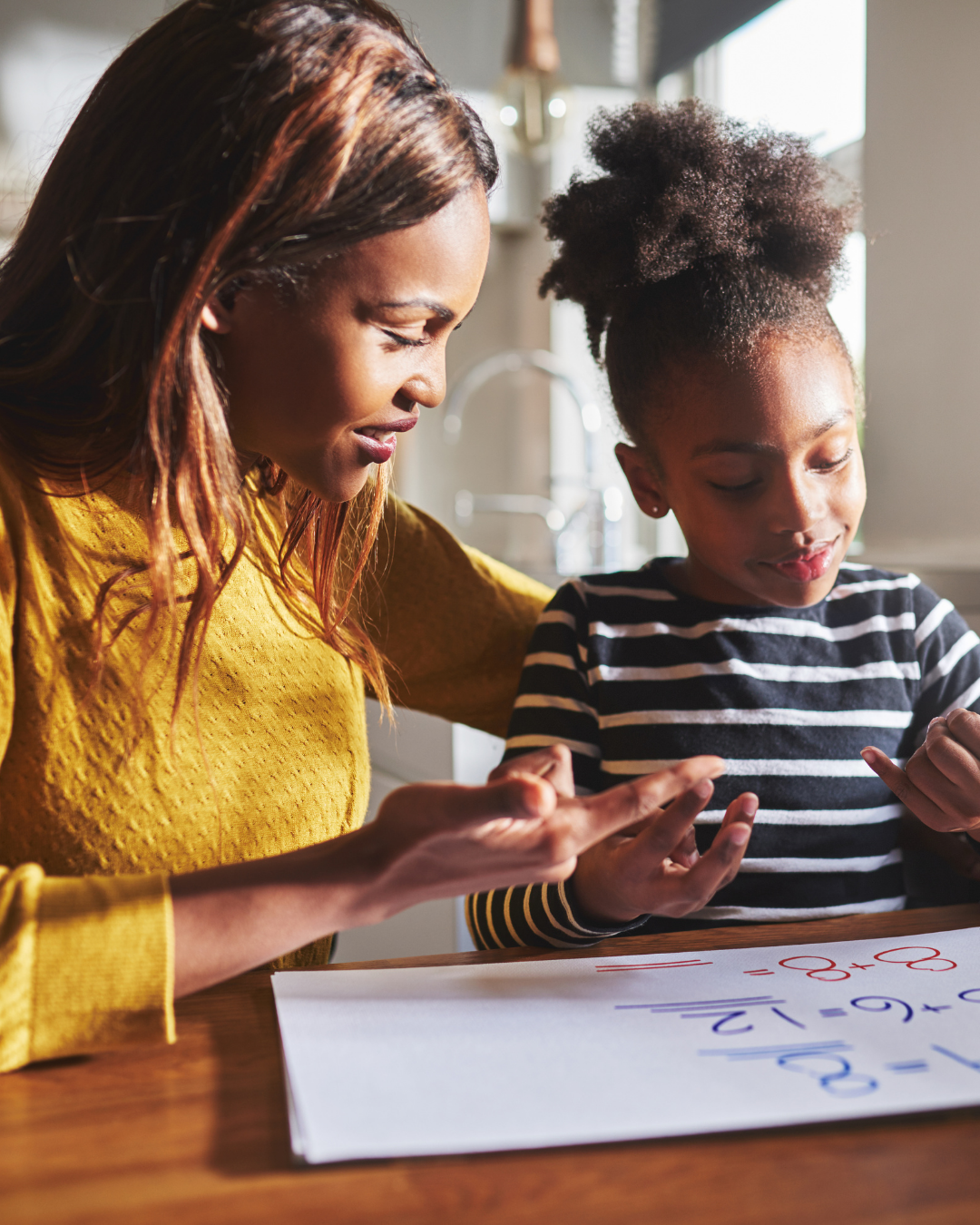 Woman and young girl learning together at a table.