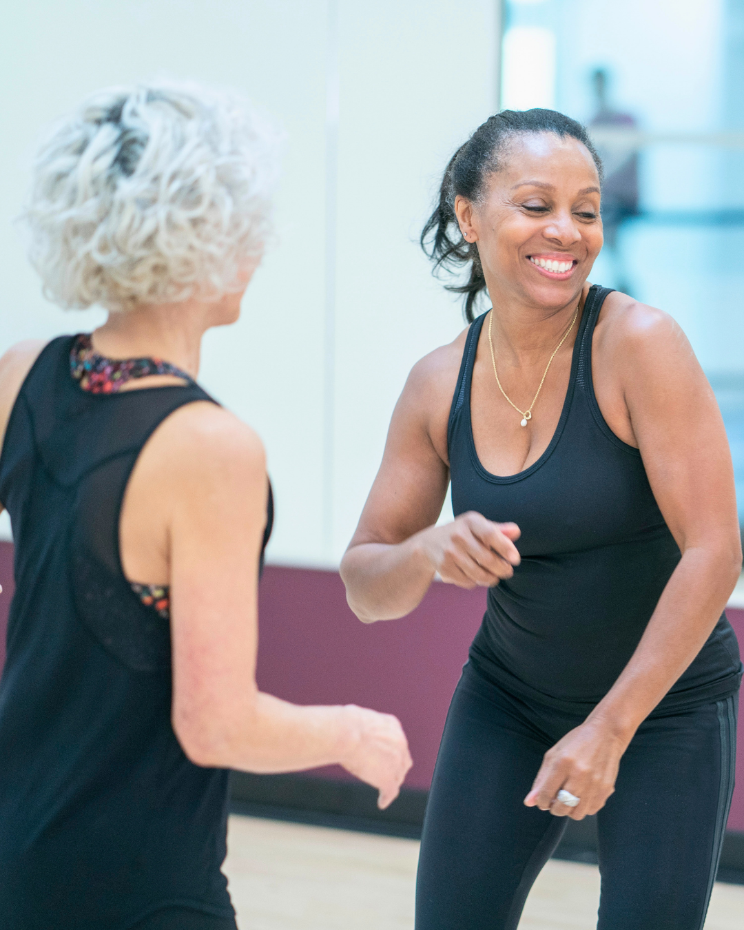 Two women dancing and smiling in a dance studio.